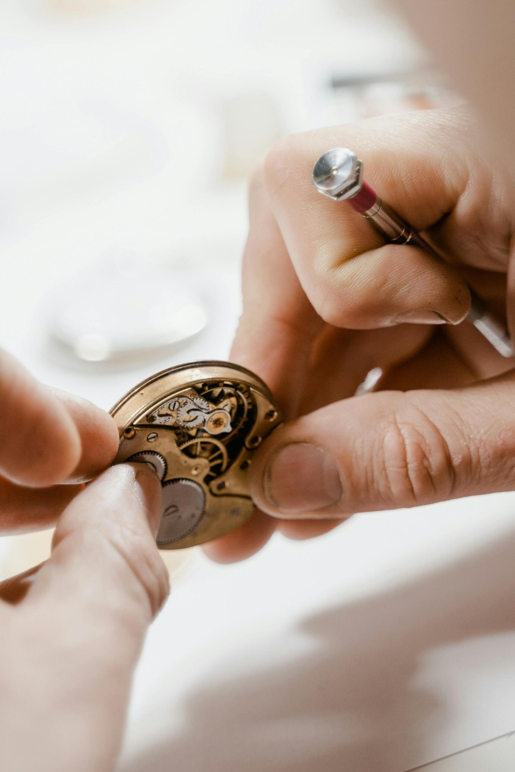 Close-up view of skilled hands repairing a watch with precision tools.